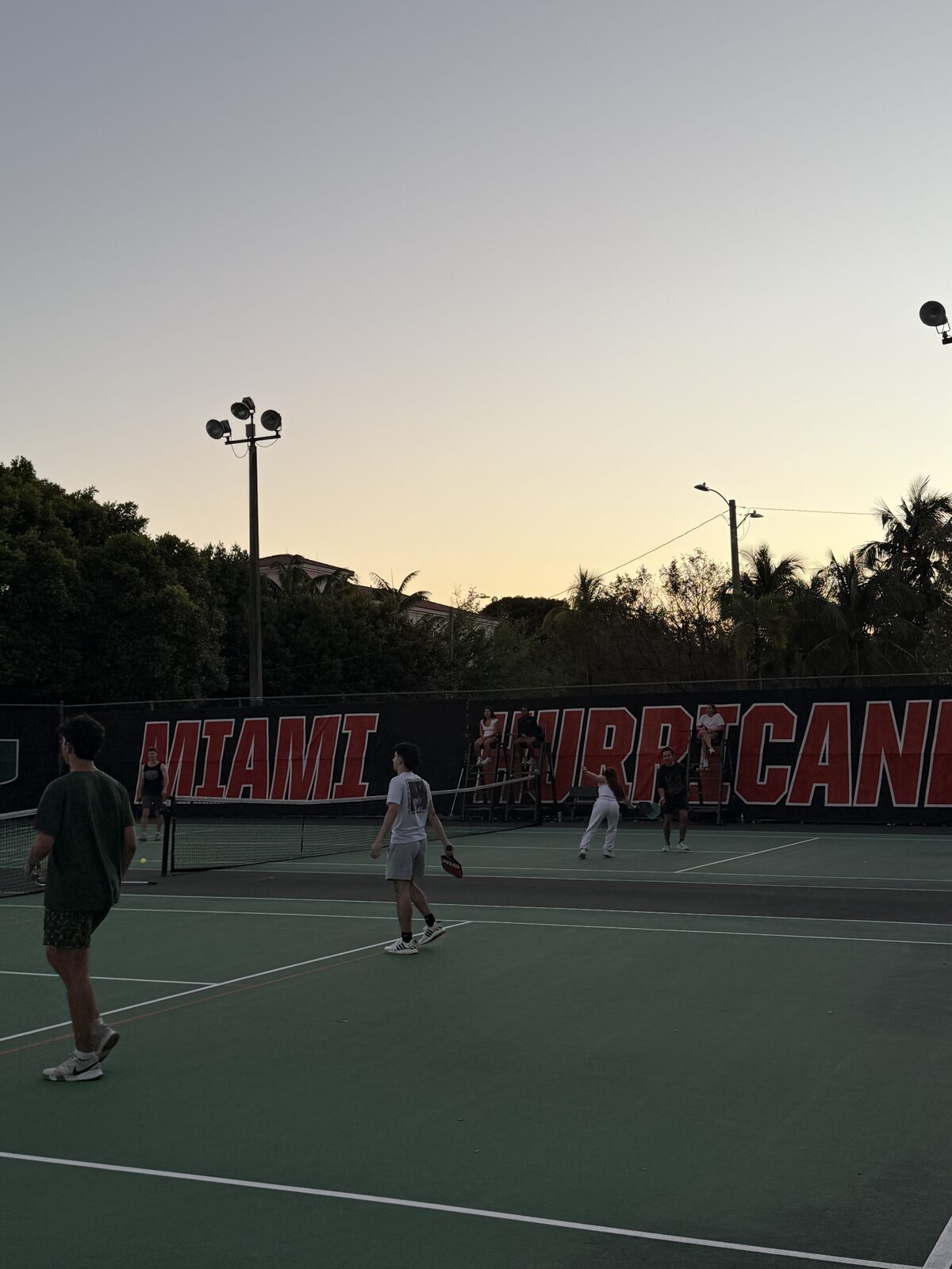 Brothers playing on the campus tennis courts at sunset