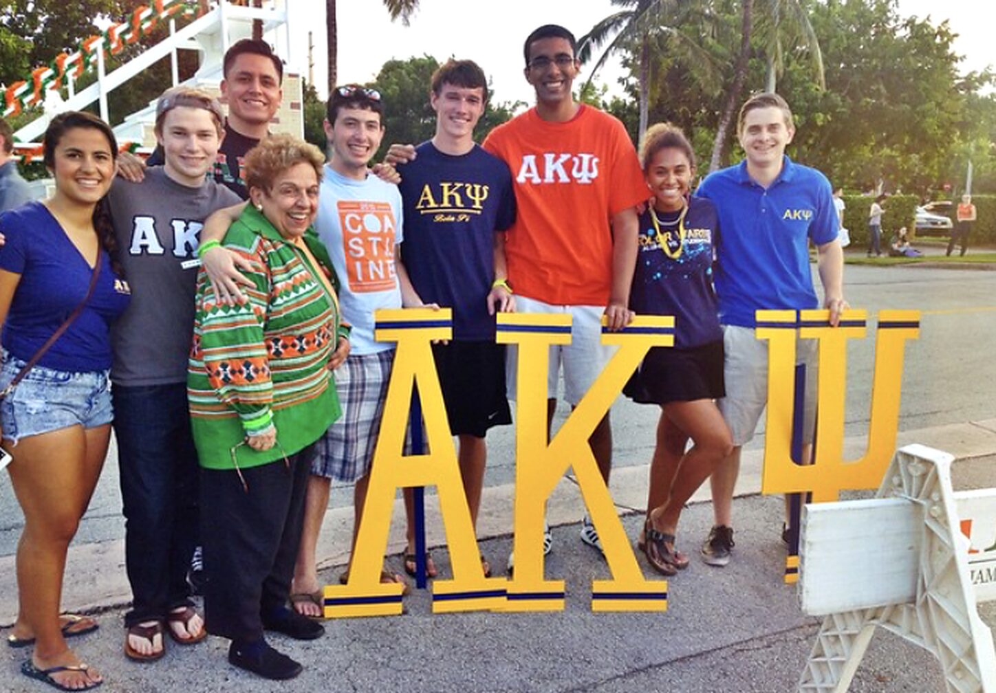 Brothers and a guest with the AKPsi letters at an outdoor event