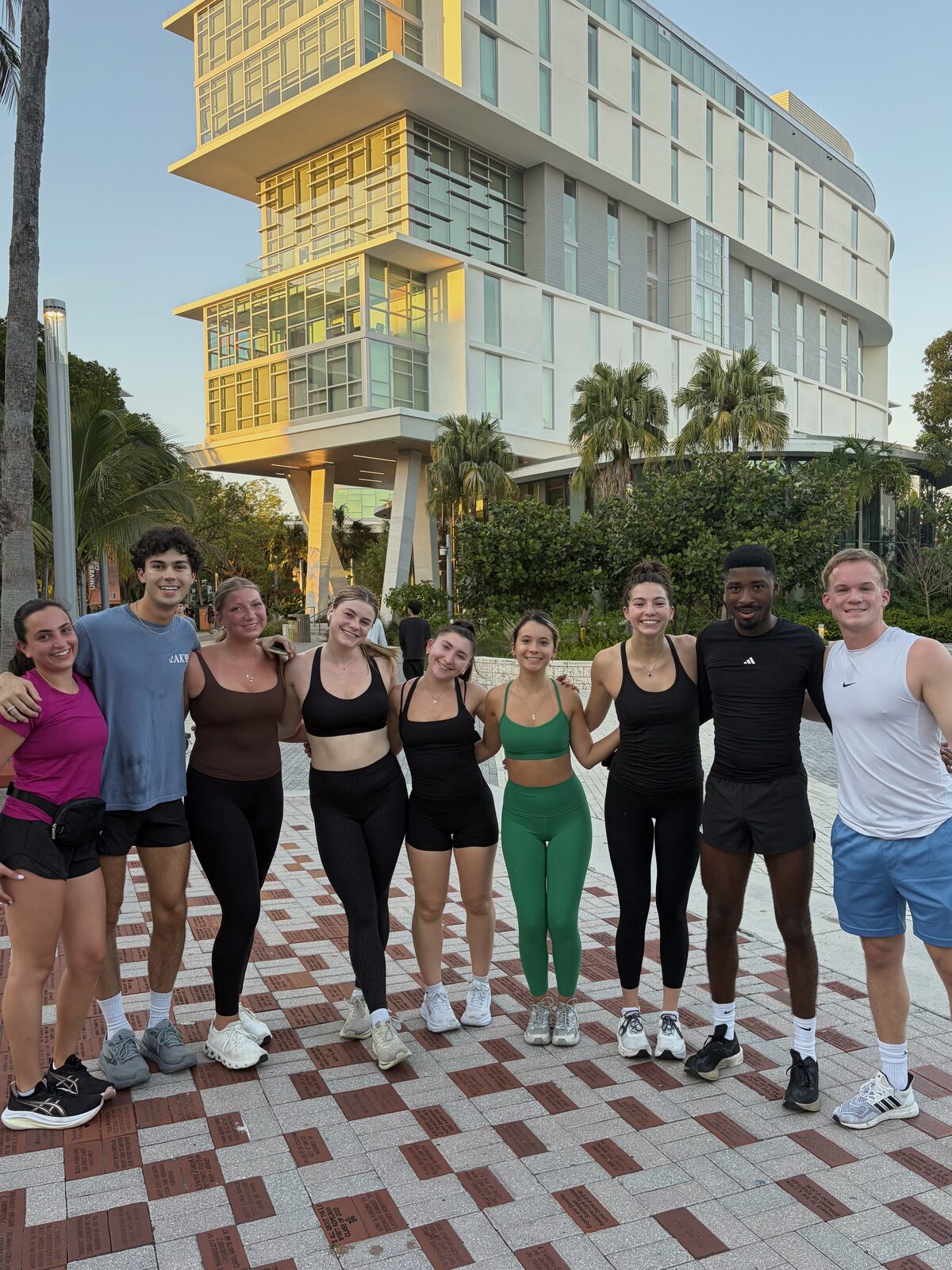 Brothers at a group workout in front of a campus building